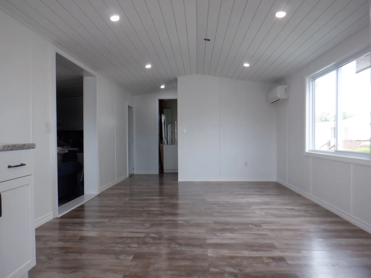Bright open concept interior with vaulted shiplap ceiling and vinyl plank floor