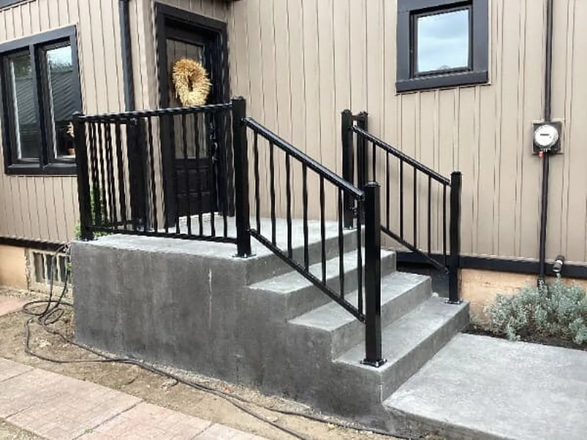 Poured concrete entry steps with black aluminum picket railings