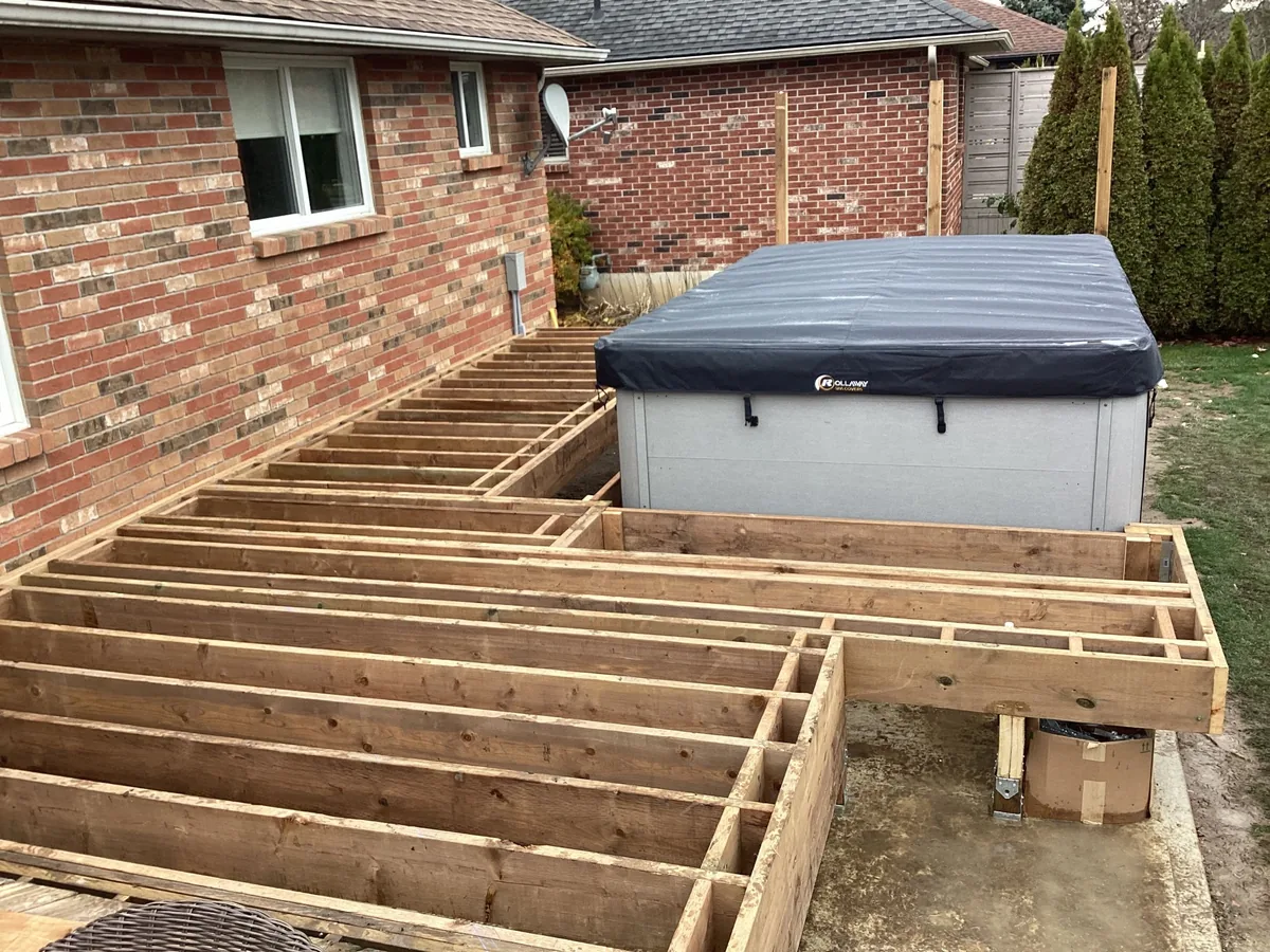 Deck framing progress around a backyard hot tub