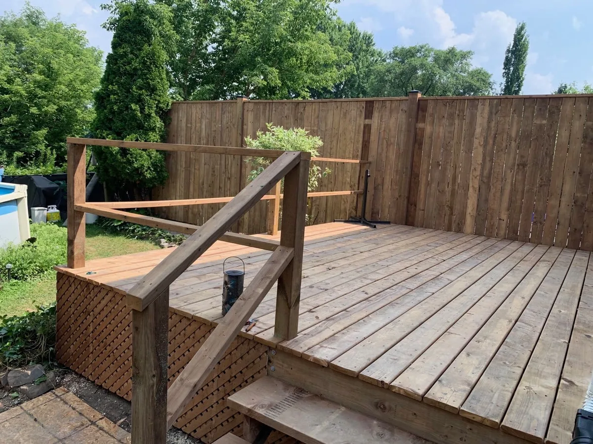 Backyard cedar deck with wood railings and privacy fence