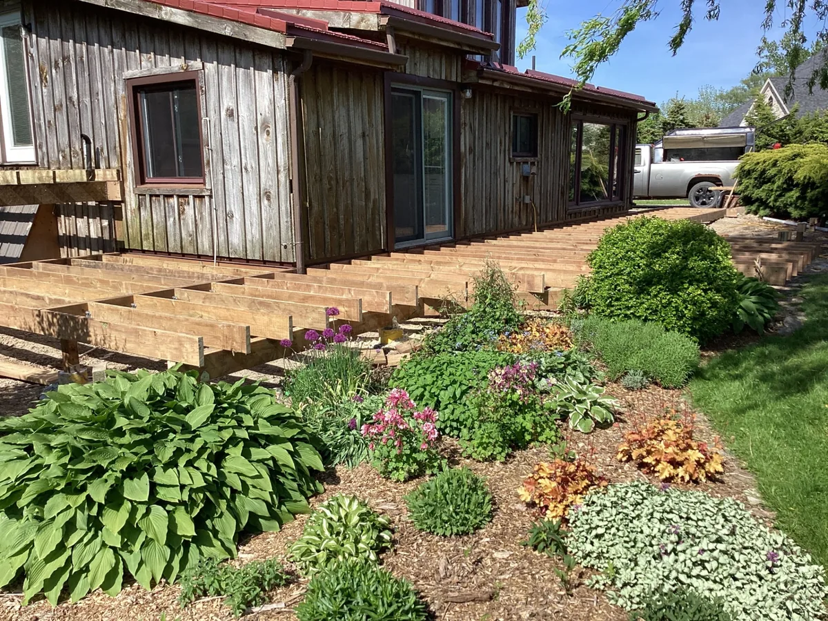 Wraparound deck framing installed along rustic home exterior