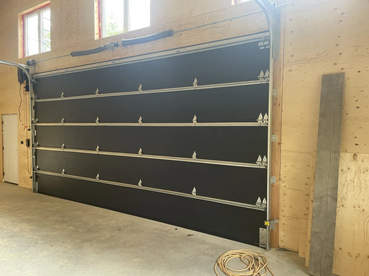 New black insulated overhead garage door installed in custom shop