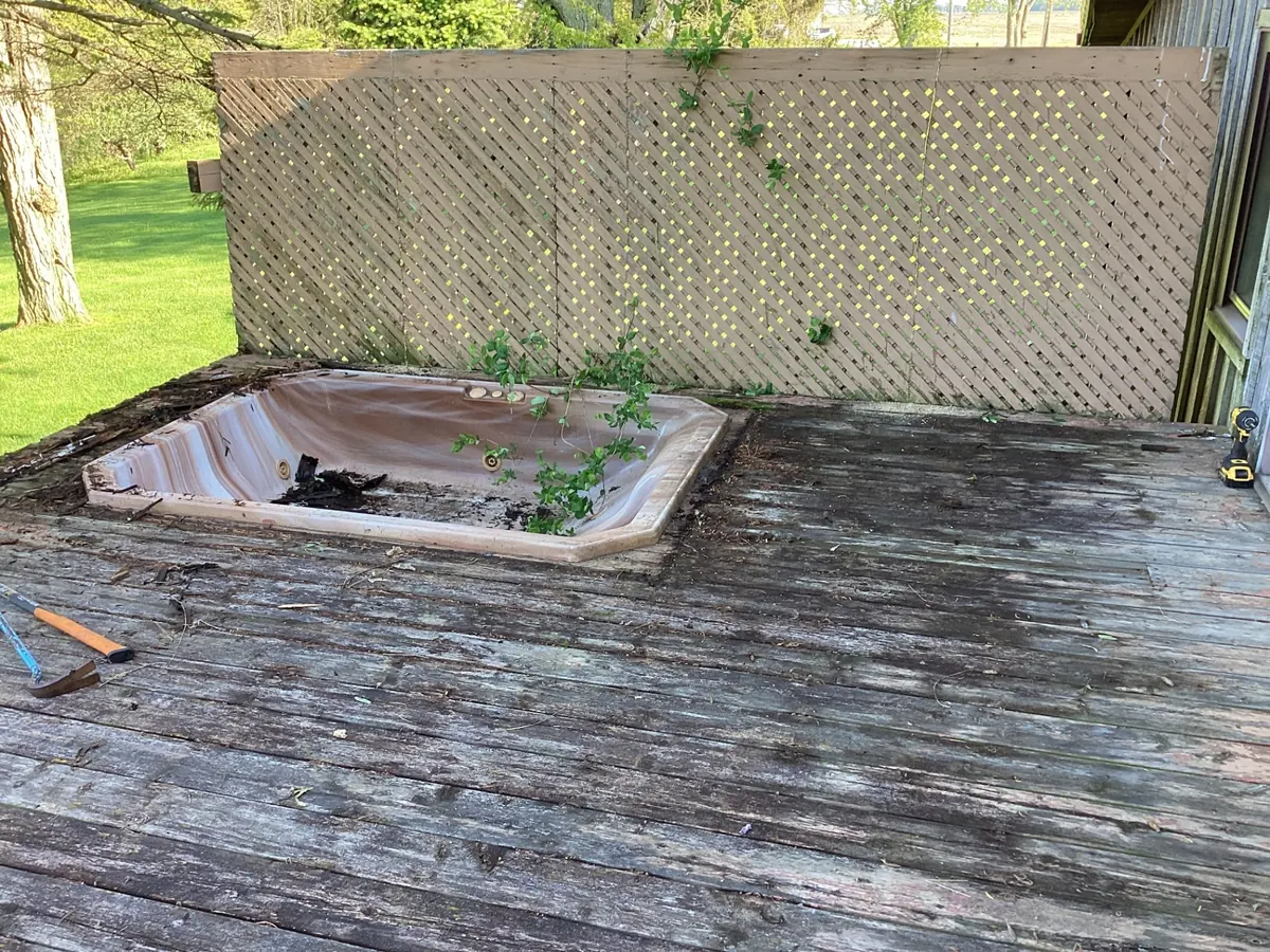 Rotting deck boards surrounding an old recessed hot tub before demolition