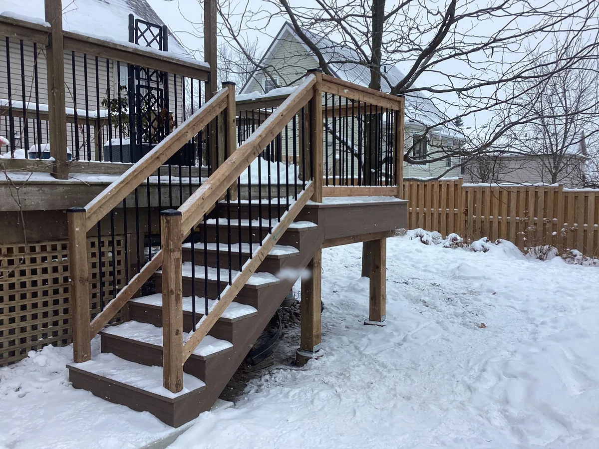 Composite deck stairs with black picket railings in winter