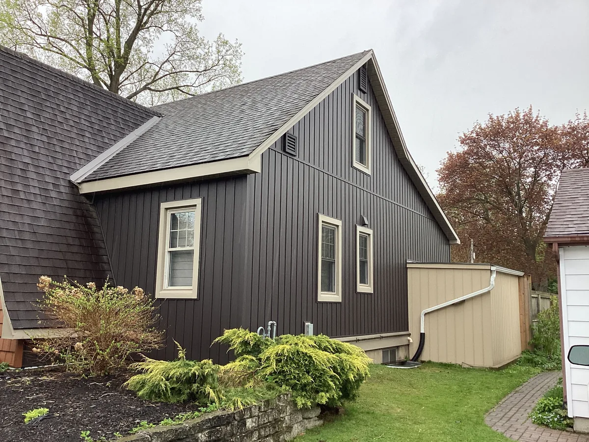 Dark board and batten side elevation with light trim and landscaped yard